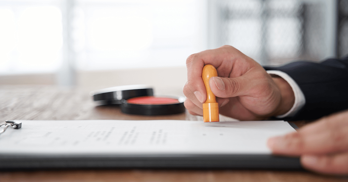 close-up of a Japanese businessman’s hand stamping a document with a company seal