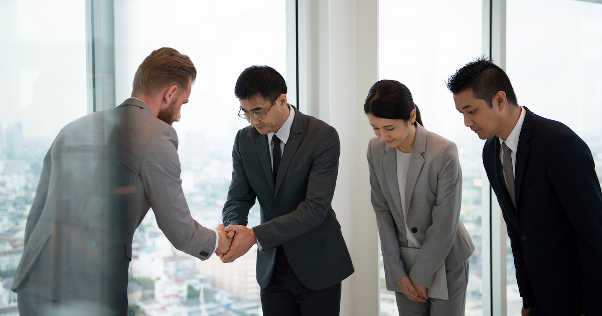 People shaking hands and bowing at japanese business meeting